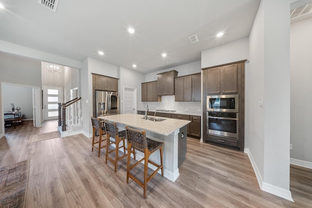 29023 Laurel Grove Ln, Fulshear, TX 77441 - kitchen featuring appliances with stainless steel finishes, a sink, a kitchen island with sink, a breakfast bar, and light wood-style floors