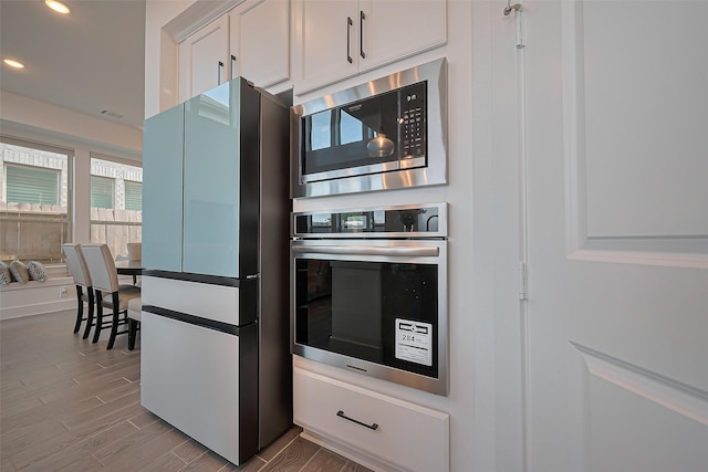 11251 Buchanan Coves Ln, Cypress, TX 77433 - kitchen with stainless steel appliances, recessed lighting, wood finished floors, and white cabinetry