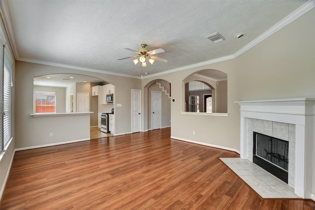 7818 Desert Canyon Ct, Houston, TX 77041 - unfurnished living room with ceiling fan, light wood-style floors, a textured ceiling, a tiled fireplace, and baseboards