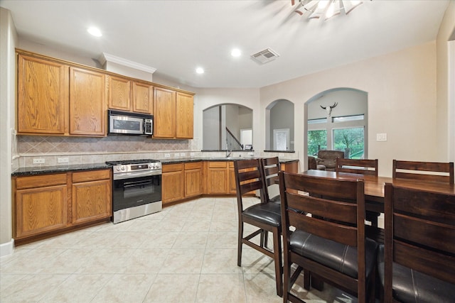 18411 S Raven Shore Dr, Cypress, TX 77433 - kitchen featuring stainless steel appliances, decorative backsplash, arched walkways, recessed lighting, and light tile patterned floors