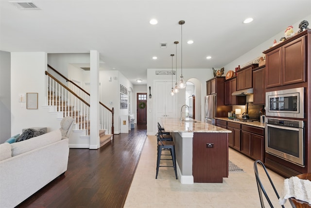 2114 Holly Manor Ct, Katy, TX 77493 - kitchen with stainless steel appliances, open floor plan, under cabinet range hood, a sink, and a breakfast bar