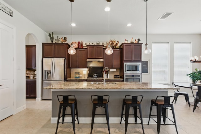 2114 Holly Manor Ct, Katy, TX 77493 - kitchen with appliances with stainless steel finishes, backsplash, arched walkways, a breakfast bar, and recessed lighting
