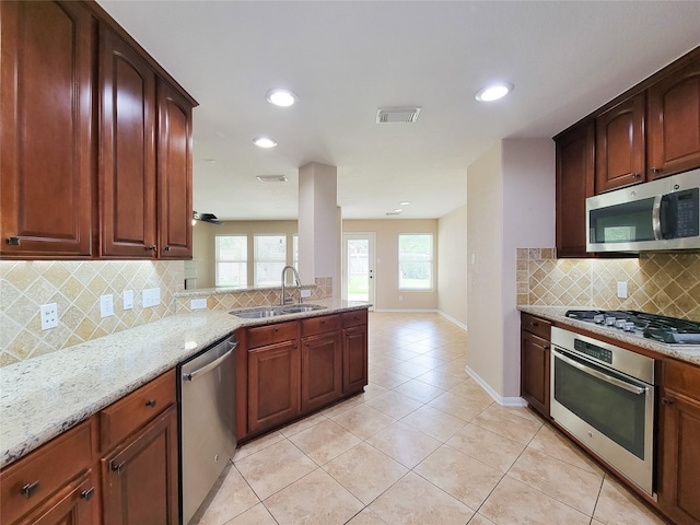 21123 Amber Crossing Dr, Richmond, TX 77406 - kitchen with stainless steel appliances, a sink, light tile patterned flooring, light stone countertops, and backsplash