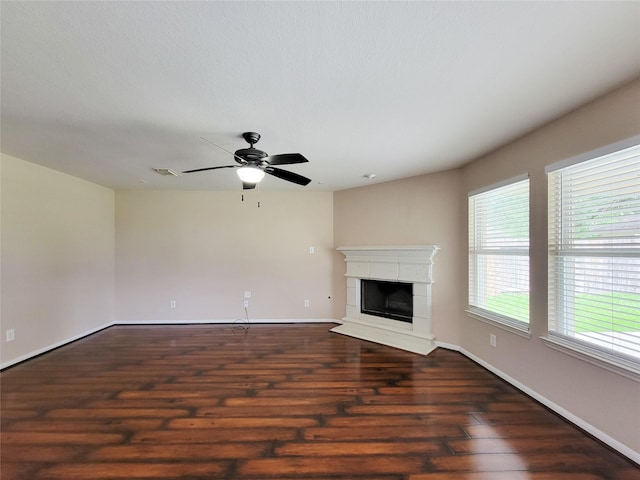 21123 Amber Crossing Dr, Richmond, TX 77406 - unfurnished living room with dark wood-style floors, a ceiling fan, baseboards, and a fireplace with raised hearth