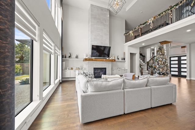 27927 Indigo Ridge Dr, Fulshear, TX 77441 - living area with a high ceiling, a glass covered fireplace, wood finished floors, stairway, and a chandelier