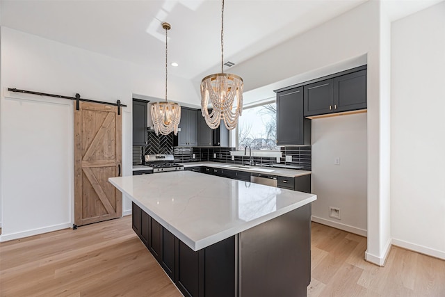 2320 Mills St, Houston, TX 77026 - kitchen featuring a chandelier, light wood finished floors, tasteful backsplash, a center island, and a barn door