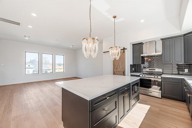 2320 Mills St, Houston, TX 77026 - kitchen featuring appliances with stainless steel finishes, wall chimney range hood, a chandelier, backsplash, and a center island