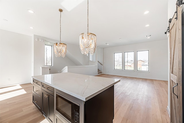 2320 Mills St, Houston, TX 77026 - kitchen featuring stainless steel microwave, a chandelier, healthy amount of natural light, a barn door, and recessed lighting