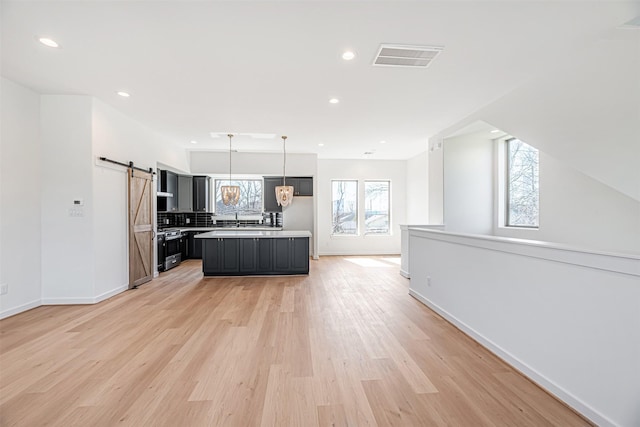 2320 Mills St, Houston, TX 77026 - kitchen featuring a barn door, open floor plan, light countertops, baseboards, and recessed lighting