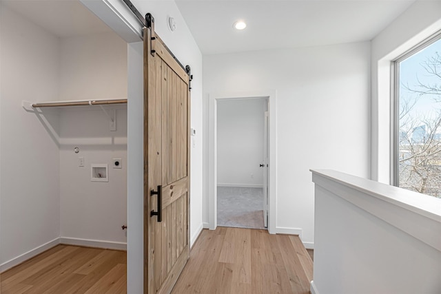 2320 Mills St, Houston, TX 77026 - laundry area with a barn door, hookup for an electric dryer, light wood-style floors, washer hookup, and baseboards