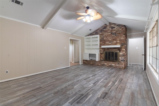 228 Hickory St, Huntsville, TX 77320 - unfurnished living room with wood finished floors, ceiling fan, a brick fireplace, and wooden walls