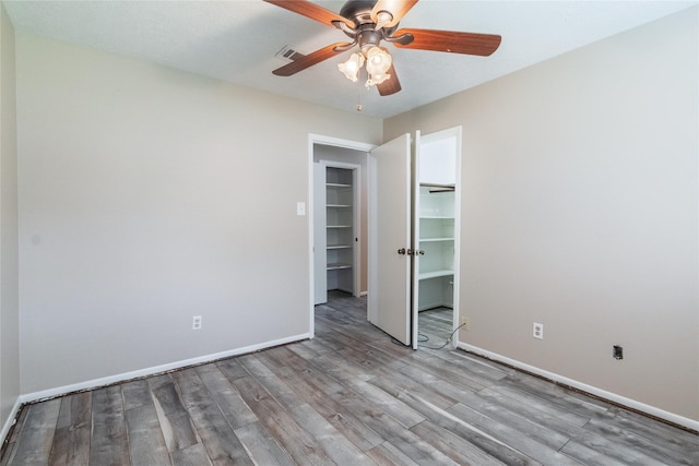 228 Hickory St, Huntsville, TX 77320 - unfurnished bedroom featuring wood finished floors, baseboards, a closet, a ceiling fan, and a spacious closet