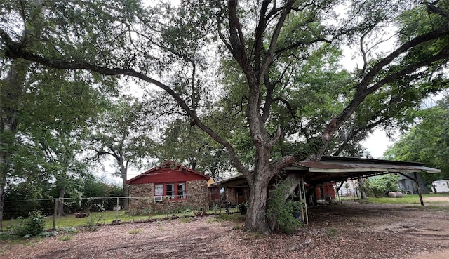 22606 Fm 359th Rd, Hempstead, TX 77445 - view of side of home with a carport, stone siding, and dirt driveway