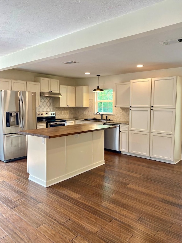 3211 Park Garden Dr, Houston, TX 77339 - kitchen featuring butcher block countertops, appliances with stainless steel finishes, under cabinet range hood, a kitchen island, and decorative backsplash