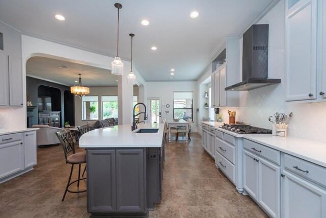 7 Fort Graham Ct, Missouri City, TX 77459 - kitchen featuring a sink, wall chimney exhaust hood, arched walkways, a breakfast bar area, and tasteful backsplash