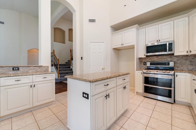 4919 Fern Cove Dr, Baytown, TX 77521 - kitchen featuring appliances with stainless steel finishes, light tile patterned flooring, light stone countertops, tasteful backsplash, and white cabinetry