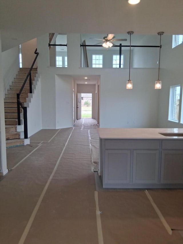 3603 Crosspointe Pass, Angleton, TX 77515 - kitchen featuring a towering ceiling, ceiling fan, gray cabinets, hanging light fixtures, and light countertops