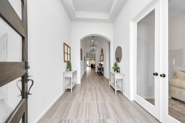 1311 Hudgins Pass, Richmond, TX 77469 - foyer entrance featuring arched walkways, french doors, a raised ceiling, baseboards, and light tile patterned floors