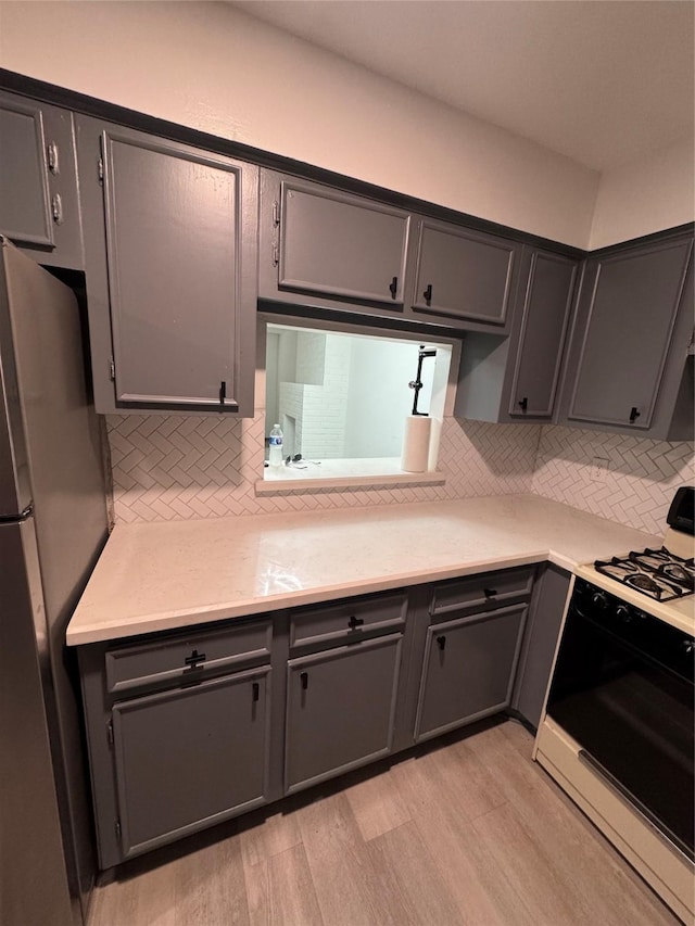 355 Audrey Ln Unit 355, Houston, TX 77015 - kitchen featuring freestanding refrigerator, range with gas cooktop, light wood-type flooring, and tasteful backsplash