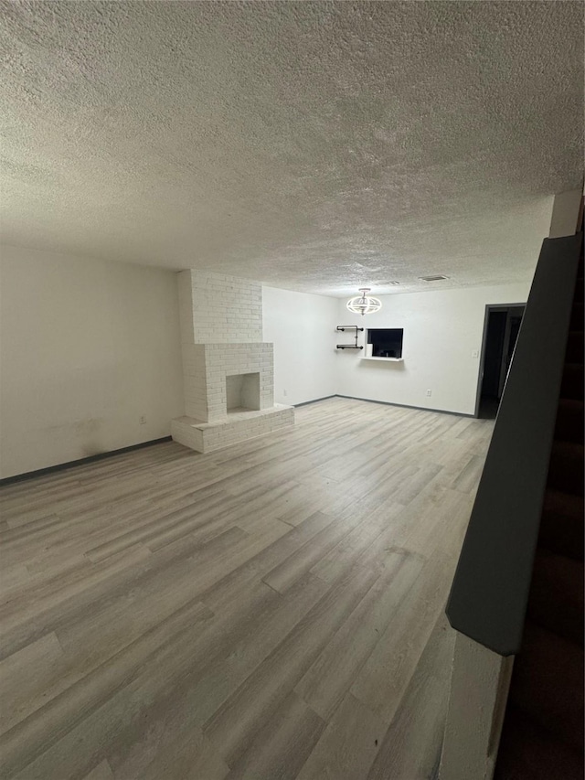 355 Audrey Ln Unit 355, Houston, TX 77015 - unfurnished living room featuring a textured ceiling, wood finished floors, a brick fireplace, and baseboards