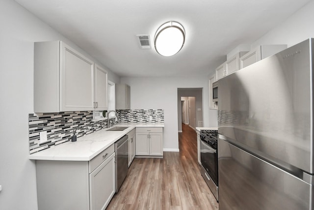3111 Tanglebriar Dr, Pasadena, TX 77503 - kitchen with appliances with stainless steel finishes, a sink, light wood-type flooring, tasteful backsplash, and baseboards