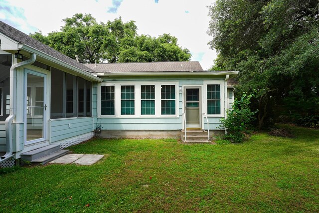 1514 Laurel St, La Marque, TX 77568 - back of house featuring entry steps, a lawn, a sunroom, and roof with shingles