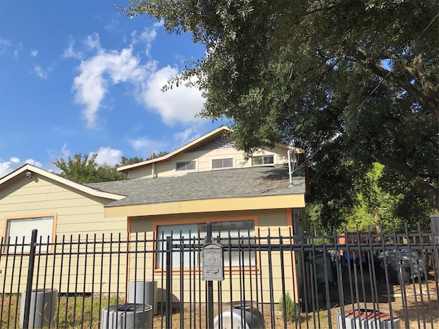 9317 Homestead Rd, Houston, TX 77016 - view of front facade featuring a shingled roof, a fenced front yard, and central AC