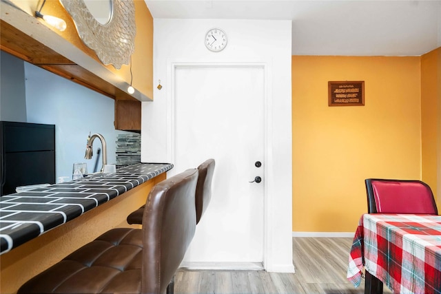 3015 Walnut Bend Ln Unit 37, Houston, TX 77042 - kitchen featuring light wood-style floors, black refrigerator, baseboards, and a breakfast bar area