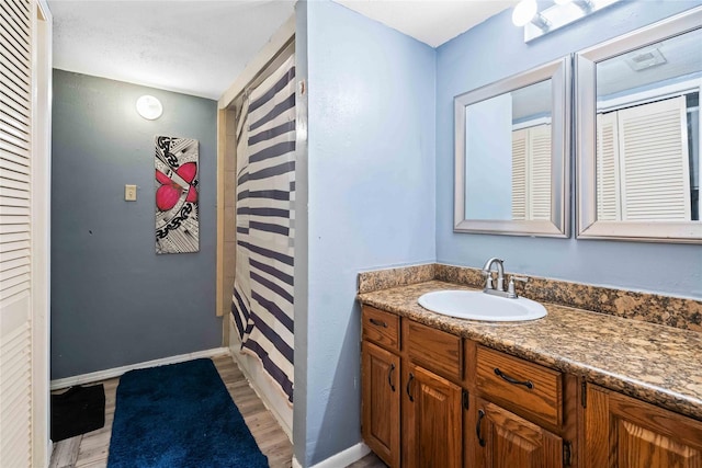 3015 Walnut Bend Ln Unit 37, Houston, TX 77042 - bathroom featuring wood finished floors, vanity, baseboards, and a closet