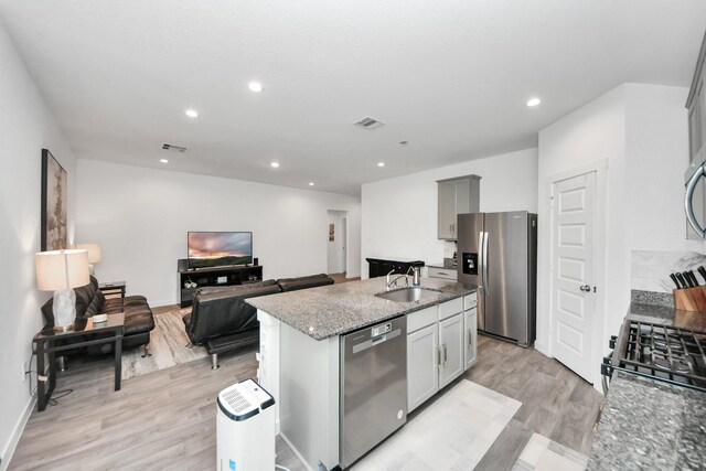 31811 Whittis Hill Way, Fulshear, TX 77441 - kitchen with stainless steel appliances, dark stone countertops, light wood-type flooring, a kitchen island with sink, and open floor plan