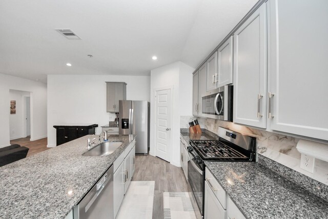 31811 Whittis Hill Way, Fulshear, TX 77441 - kitchen featuring appliances with stainless steel finishes, a sink, stone countertops, recessed lighting, and light wood-style floors