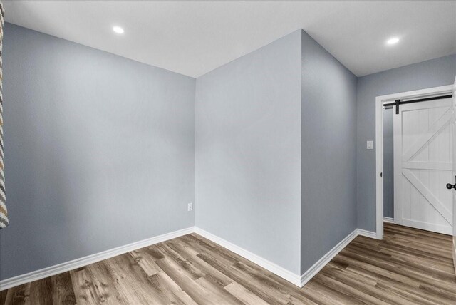 12153 24th St, Santa Fe, TX 77510 - spare room featuring wood finished floors, baseboards, a barn door, and recessed lighting