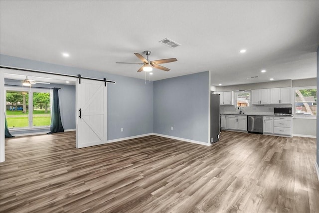 12153 24th St, Santa Fe, TX 77510 - unfurnished living room with ceiling fan, a barn door, a sink, wood finished floors, and recessed lighting