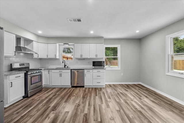 12153 24th St, Santa Fe, TX 77510 - kitchen featuring stainless steel appliances, wall chimney exhaust hood, white cabinets, and recessed lighting