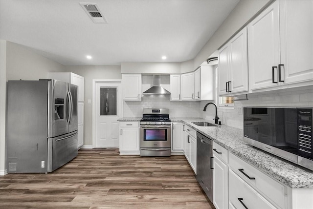 12153 24th St, Santa Fe, TX 77510 - kitchen featuring appliances with stainless steel finishes, a sink, wall chimney exhaust hood, white cabinetry, and recessed lighting