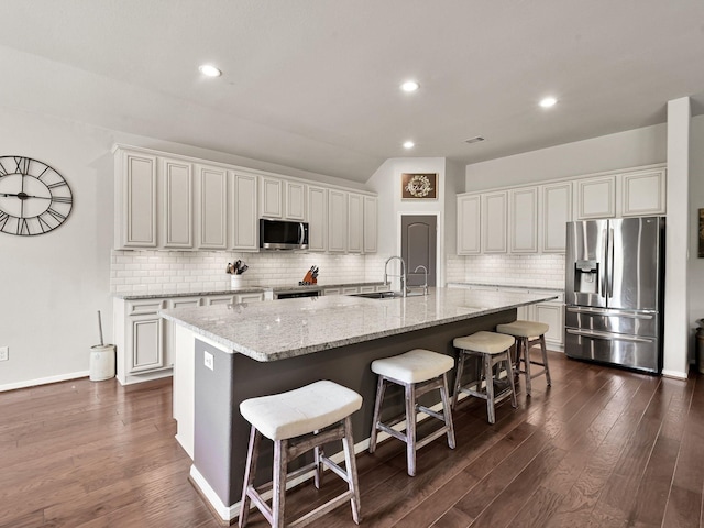 9175 White Tail Dr, Conroe, TX 77303 - kitchen featuring appliances with stainless steel finishes, a spacious island, tasteful backsplash, a sink, and a breakfast bar