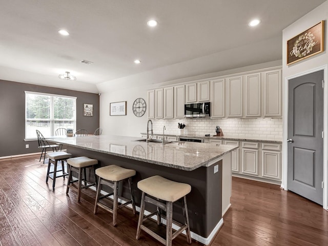 9175 White Tail Dr, Conroe, TX 77303 - kitchen with stainless steel microwave, a breakfast bar, dark wood-style floors, a sink, and recessed lighting
