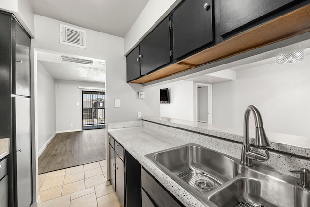 206 Plaza Verde Dr Unit D35, Houston, TX 77038 - kitchen featuring a sink, light countertops, light tile patterned floors, and dark cabinetry
