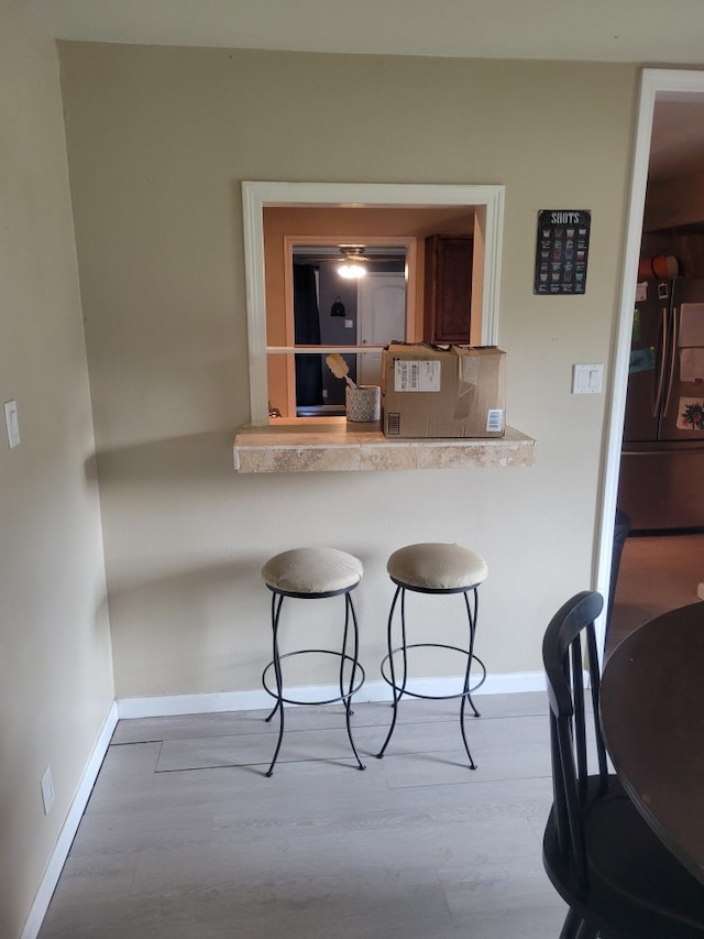 118 Whiting St, Galveston, TX 77550 - kitchen featuring stainless steel fridge, a breakfast bar area, wood finished floors, and light countertops