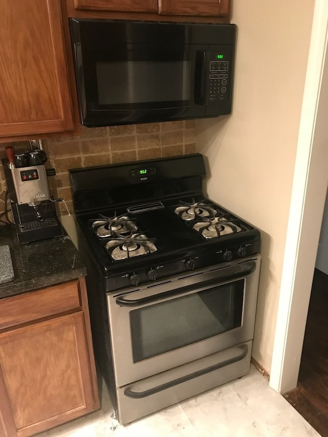 118 Whiting St, Galveston, TX 77550 - kitchen with gas range oven, black microwave, backsplash, brown cabinets, and dark stone countertops
