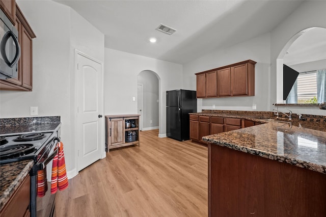 5527 Snapping Turtle Rd, Baytown, TX 77523 - kitchen featuring black appliances, arched walkways, dark stone countertops, light wood-style flooring, and baseboards