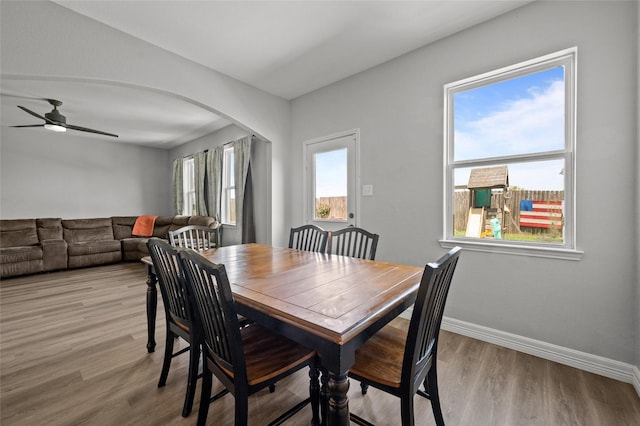 5527 Snapping Turtle Rd, Baytown, TX 77523 - dining room featuring arched walkways, light wood-type flooring, a ceiling fan, and baseboards