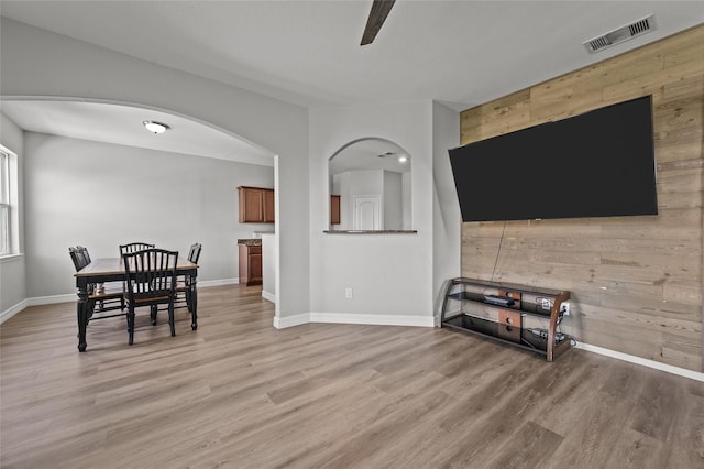 5527 Snapping Turtle Rd, Baytown, TX 77523 - dining room with wood walls, light wood-style flooring, arched walkways, and baseboards