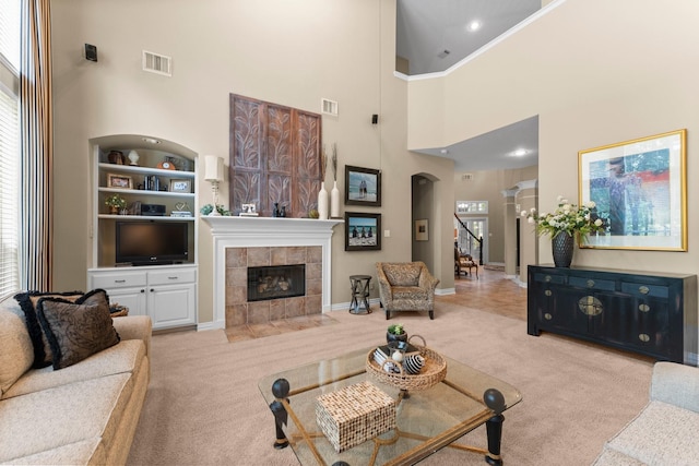 3 Forest Steppes Ct, The Woodlands, TX 77382 - carpeted living area featuring a towering ceiling, plenty of natural light, built in shelves, a tile fireplace, and arched walkways