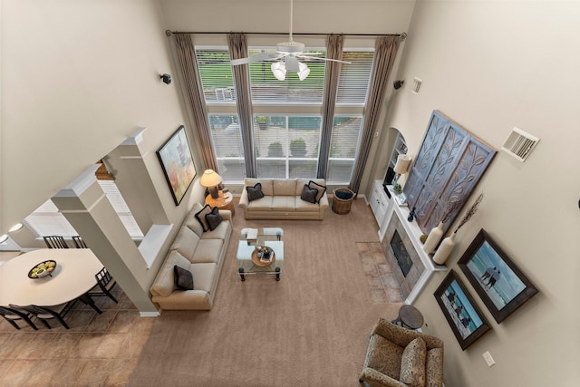 3 Forest Steppes Ct, The Woodlands, TX 77382 - carpeted living room featuring a towering ceiling, a ceiling fan, a fireplace with flush hearth, and baseboards