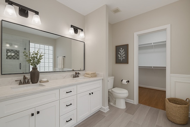 1108 W 22nd St, Houston, TX 77008 - full bath with toilet, a stall shower, double vanity, a walk in closet, and wood finished floors