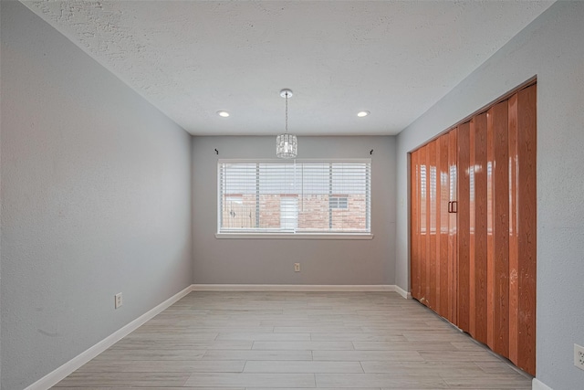 19531 Lazy Valley Dr, Katy, TX 77449 - unfurnished dining area featuring light wood-style flooring, a chandelier, a textured ceiling, baseboards, and recessed lighting