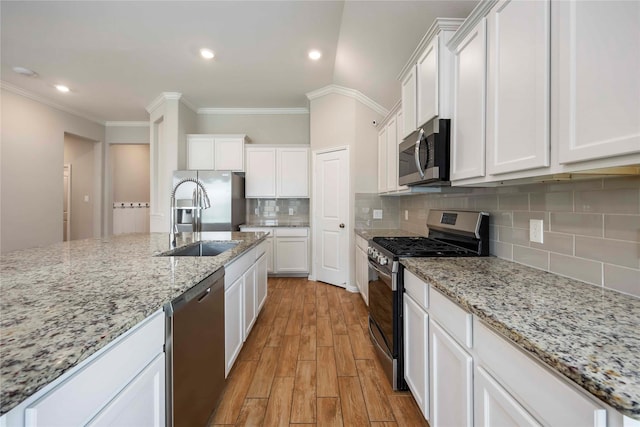 3677 Pinewood Bend Ln, Spring, TX 77386 - kitchen featuring appliances with stainless steel finishes, a sink, crown molding, light wood-style flooring, and white cabinetry