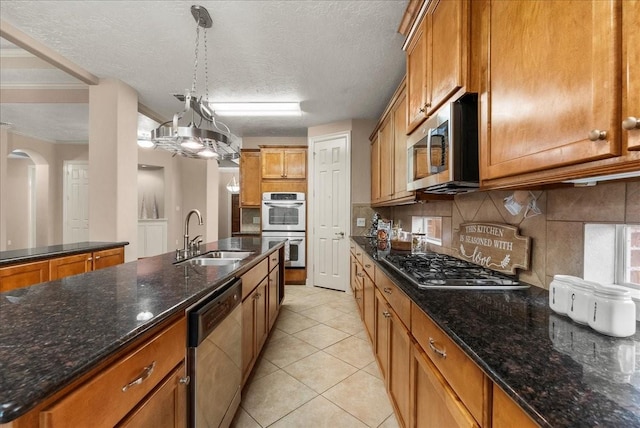 3707 Charleston St, Houston, TX 77021 - kitchen featuring appliances with stainless steel finishes, a sink, brown cabinets, tasteful backsplash, and dark stone counters