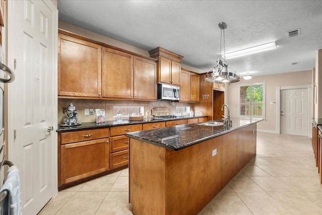 3707 Charleston St, Houston, TX 77021 - kitchen with a sink, stainless steel appliances, brown cabinets, light tile patterned flooring, and a textured ceiling